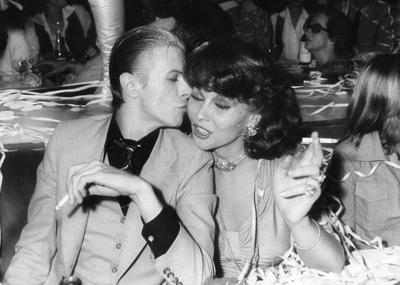 Дэвид Боуи и нидерландская певица и актриса Роми Хааг наслаждаются сигареткой в клубе Alcazar в Париже, 1976 год Веселые, люди, эпоха