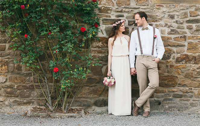 жених и невеста стоят у стены