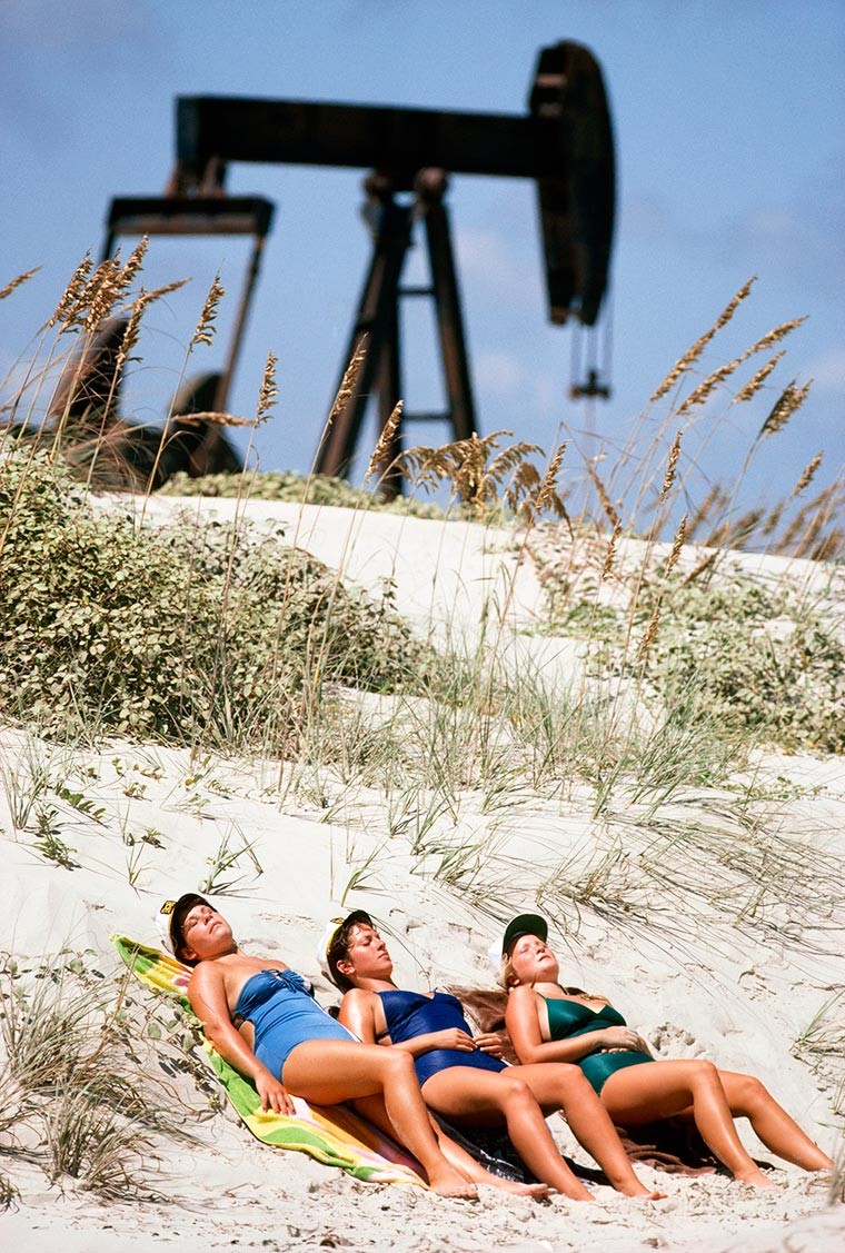 Женщины загорают на фоне нефтяной качалки, 1980 год, Остров Падре, Техас, США историческое фото, история