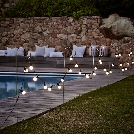 10 bistro bulb fairylights attached to hooks along the whole pool