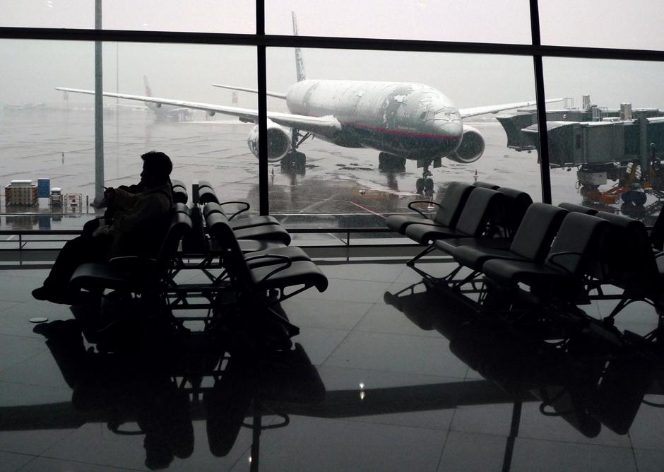 6) Заснеженный самолет виден через окно зала ожидания пассажирского терминала в международном аэропорту Пекина.