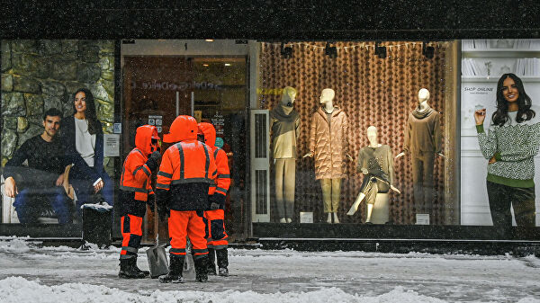 Сотрудники коммунальной службы на одной из улиц в Москве во время снегопада