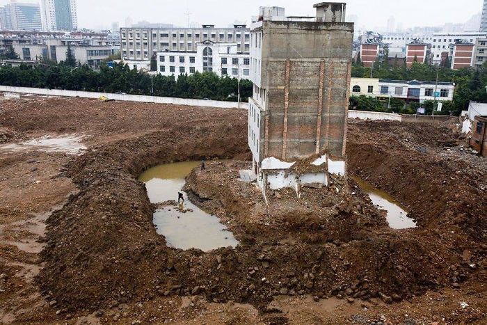 The Tenant Of This Apartment Building In Kunming, China, Has To Cross A Moat After The Contractors Dug A Ditch To Force The Last Family Out. 