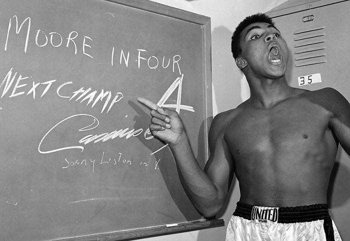 Young Muhammad Ali Points To A Sign He Wrote In His Dressing Room Before His Fight Against Archie Moore In Los Angeles, Predicting He’d Knock Moore Out In The Fourth Round, Which He Went On To Do