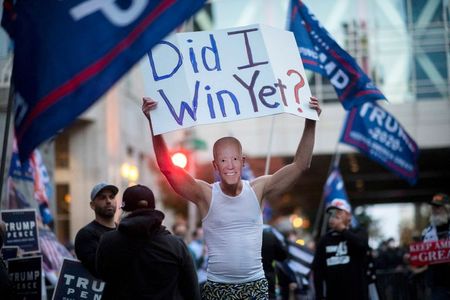 Trump supporter carries a sign while wearing a mask of U.S. Democratic presidential nominee Joe Biden during a protest outside of the Philadelphia Convention Center, where votes are still being counted two days after the presidential election, in Philadelphia, Pennsylvania, U.S. November 5, 2020. REUTERS/Mark Makela