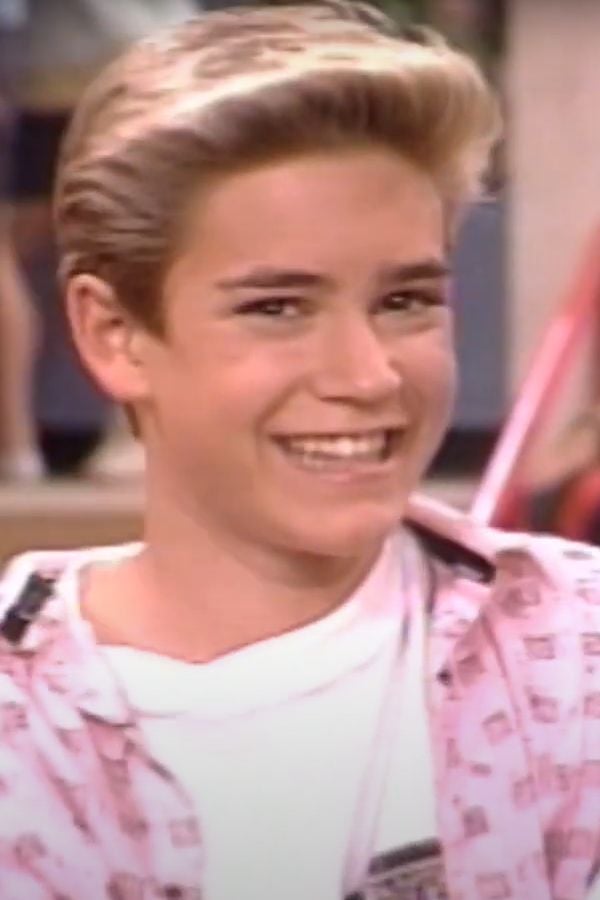 Zack smiles as he plots a new scam. - Saved By the Bell - NBC - Peacock Promo Screenshot