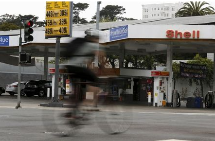 A cyclist rides past a sign showing the prices of gas at a filling station in San Francisco, California July 22, 2015. U.S. motorists' habit of filling up with costlier "premium" gasoline when pump prices drop is delivering extra profits to refiners, such as Royal Dutch Shell and traders like Noble Group. For the second time in the past decade, a sharp fall in pump prices has triggered a spike in demand for the higher-octane fuel that has far outpaced the overall rise in consumption. Picture taken July 22, 2015. To match GASOLINE-DEMAND/PREMIUM REUTERS/Robert Galbraith