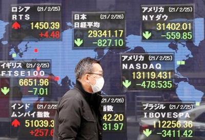 رجل يضع كمامة للوقاية من فيروس كورونا يسير أمام لوحة إلكترونية تعرض مؤشرات الأسواق في طوكيو يوم 26 فبراير شباط 2021. تصوير: كيم كيونج هون - رويترز.