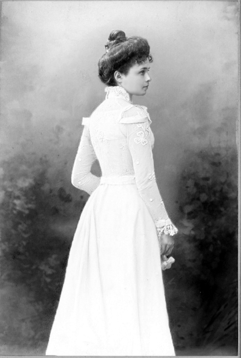 Женщина гуляет в саду в белом платье. 1900-е года.
