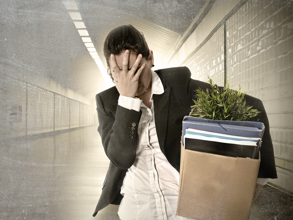 desperate depressed businesswoman fired from job carrying office belongings in cardboard box crying sad in grunge tunnel background in financial crisis and work loss concept