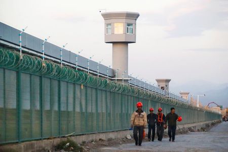 FILE PHOTO: Workers walk by the perimeter fence of what is officially known as a vocational skills education centre in Dabancheng in Xinjiang Uighur Autonomous Region, China September 4, 2018. Picture taken September 4, 2018. REUTERS/Thomas Peter/File Photo
