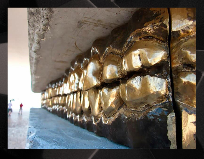 На металлические зубы давят тяжёлые бетонные блоки.
