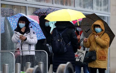 People wearing face masks shelter under umbrellas outside a department store following the outbreak of the coronavirus disease (COVID-19) in Manchester, Britain, October 26, 2020. REUTERS/Phil Noble/File Photo