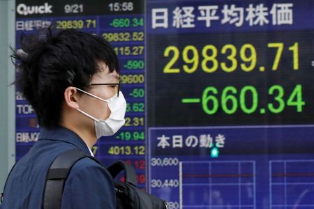 A man wearing a protective mask, amid the COVID-19 outbreak, walks past an electronic board displaying Japan's Nikkei index outside a brokerage in Tokyo, Japan, September 21, 2021. REUTERS/Kim Kyung-Hoon