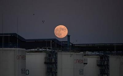 The moon rises behind the storage tanks of a local oil refinery in Omsk, Russia June 5, 2020. Picture taken June 5, 2020. REUTERS/Alexey Malgavko