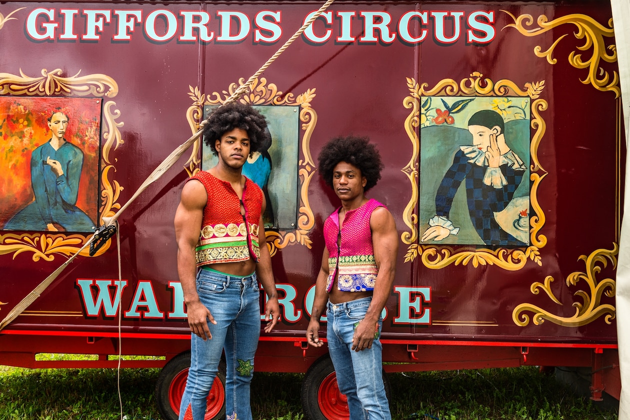 Фотография двух молодых людей, позирующих для портрета в передней части цирковой повозки.