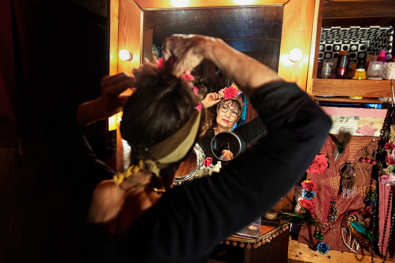 Фотография артистки перед зеркалом, готовящейся к шоу в своем фургоне.
