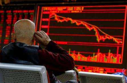 FILE PHOTO: An investor sits in front of a board showing stock information at a brokerage office in Beijing, China, December 7, 2018. REUTERS/Thomas Peter/File Photo