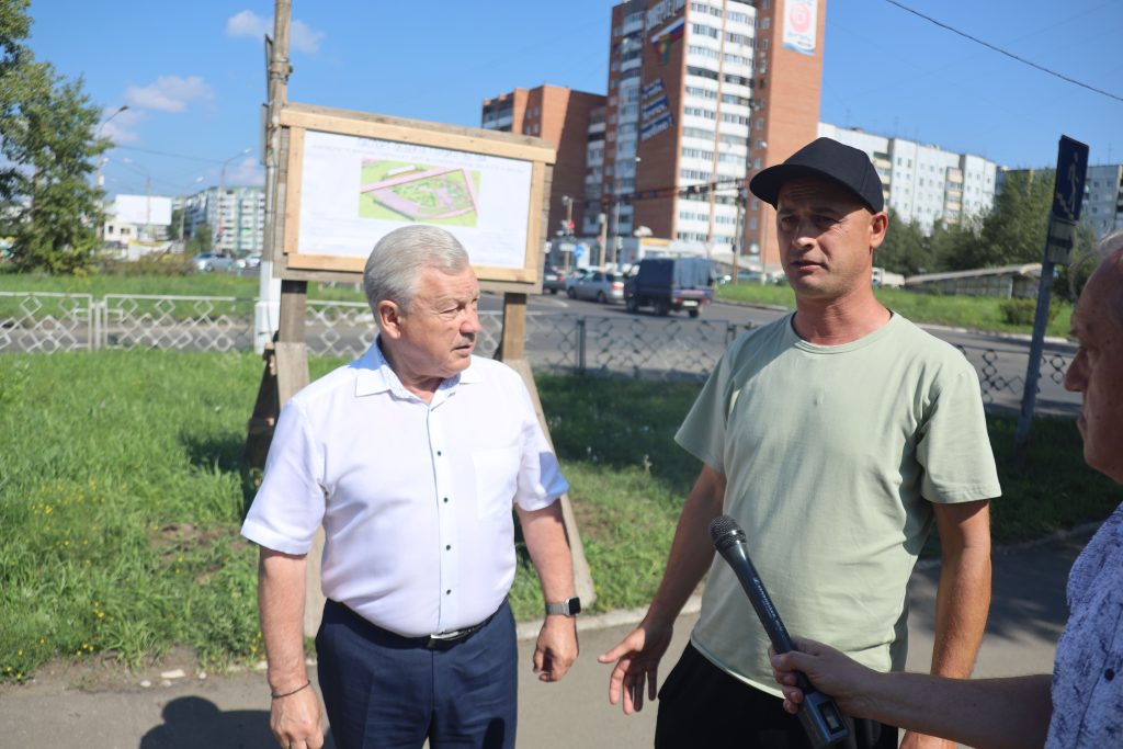 Интервью на улице со строительным планом на заднем плане.