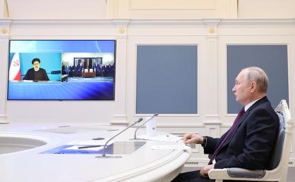 На фото: резидент РФ Владимир Путин в Кремле и президент Ирана Эбрахим Раиси (на экране) во время встречи в режиме видеоконференции, посвященной подписанию российско-иранского соглашения о сотрудничестве по созданию в Иране железной дороги "Решт - Астара"
