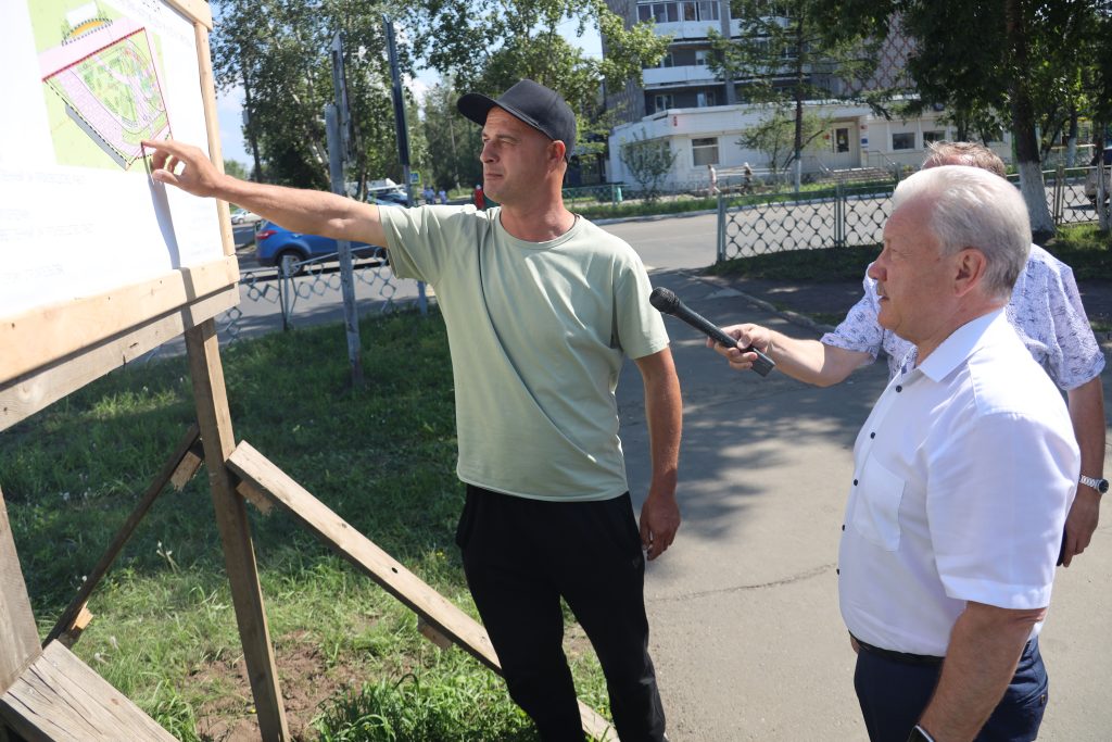 Мужчина показывает на карту, другой держит микрофон.